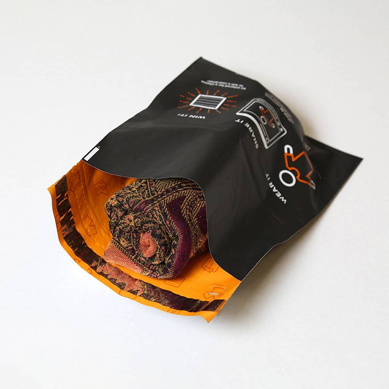 Black mailer printed inside and out, opened to show a rolled garment against a printed orange interior