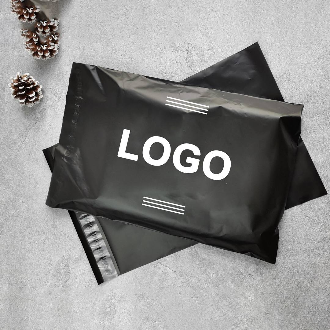 Black poly mailers arranged flat with white printed lettering and pine cones alongside