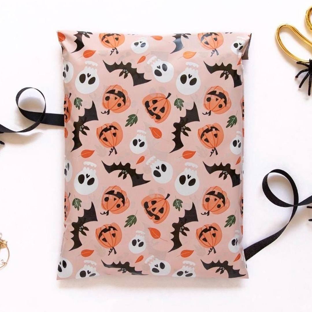 Blush pink mailer printed with a repeating pattern of pumpkins, bats and skulls