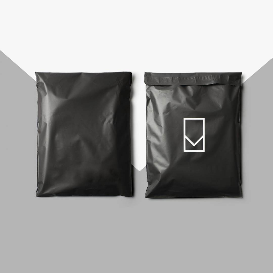 Matte black poly mailers shown front and back, one printed with a white line mark