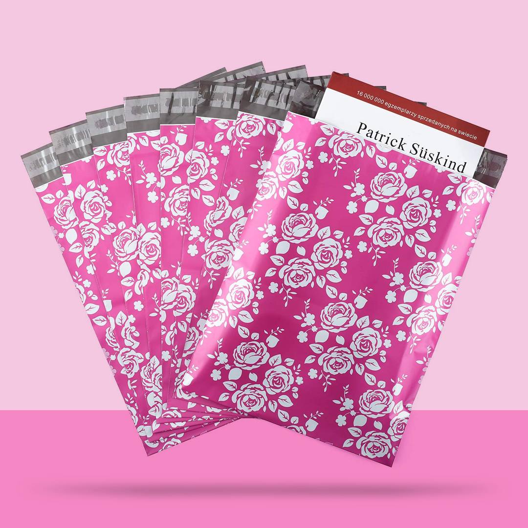 Pink poly mailers printed with a white rose pattern, one holding a paperback book