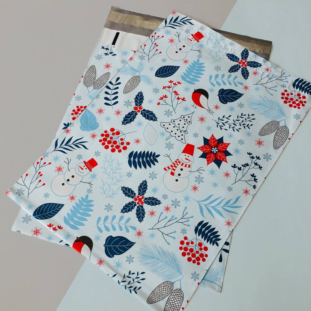 Two white mailers printed with a winter botanical pattern of holly, berries and snowmen