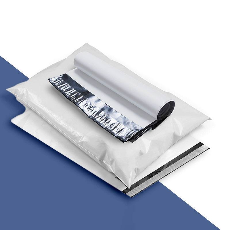 Stack of plain white poly mailers beside a roll of the same film